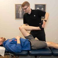 Chiropractor assessing hip flexion to find the root cause of pain at a Tulsa chiropractic clinic