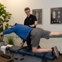 Demonstrating Bird Dog with Band at Verdant Motion Chiropractic and Rehab