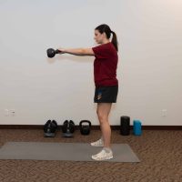 Patient performing a kettlebell swing as part of a functional rehab program with a Tulsa chiropractor